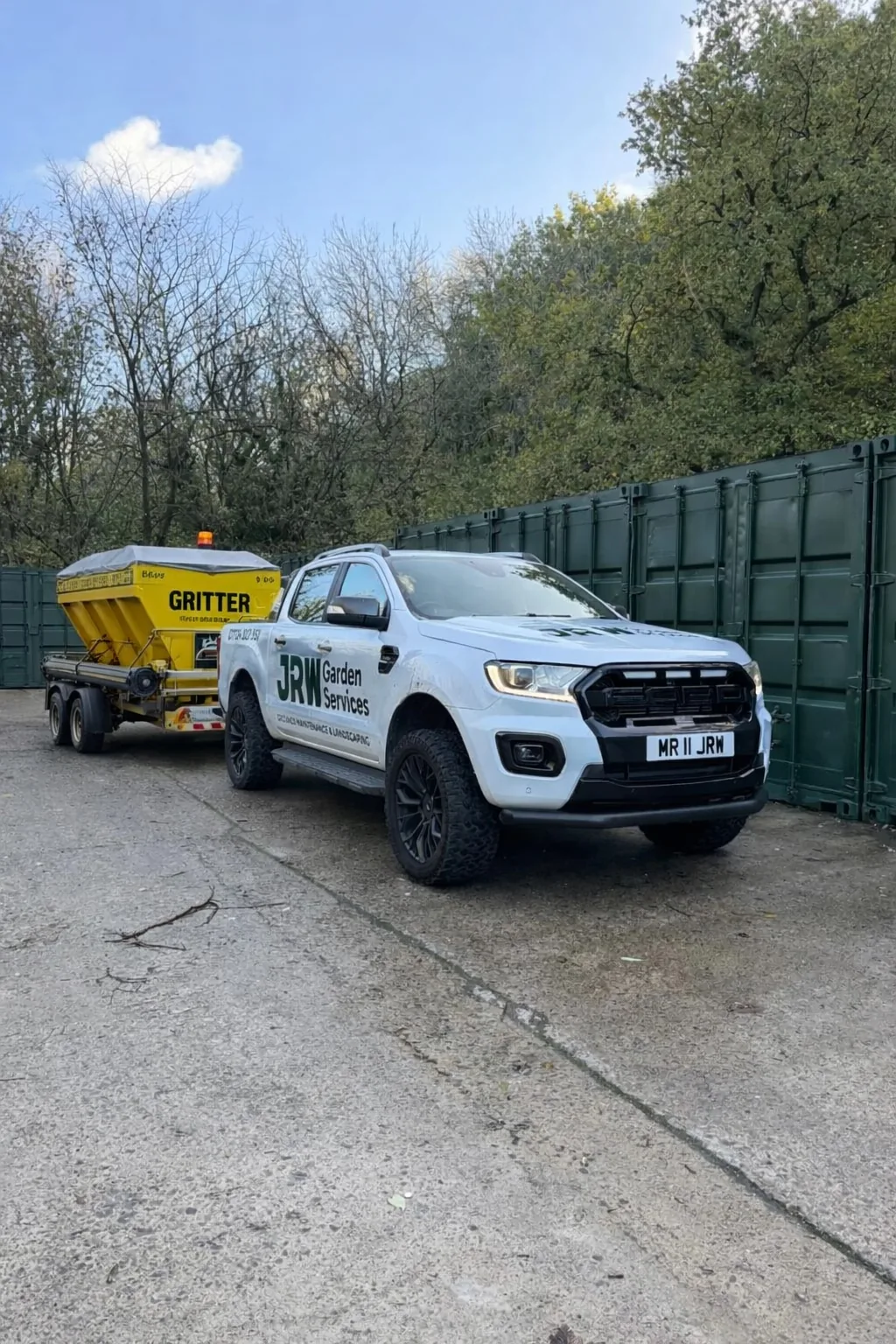 JRW Garden Services van towing a winter gritter trailer on a commercial site