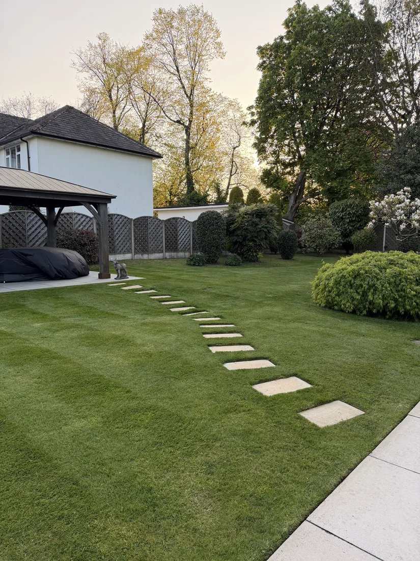 Striped lawn with a stepping-stone path leading across to a garden gazebo