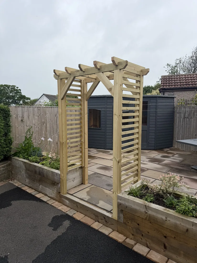 Timber pergola on a newly laid sandstone patio with raised sleeper beds