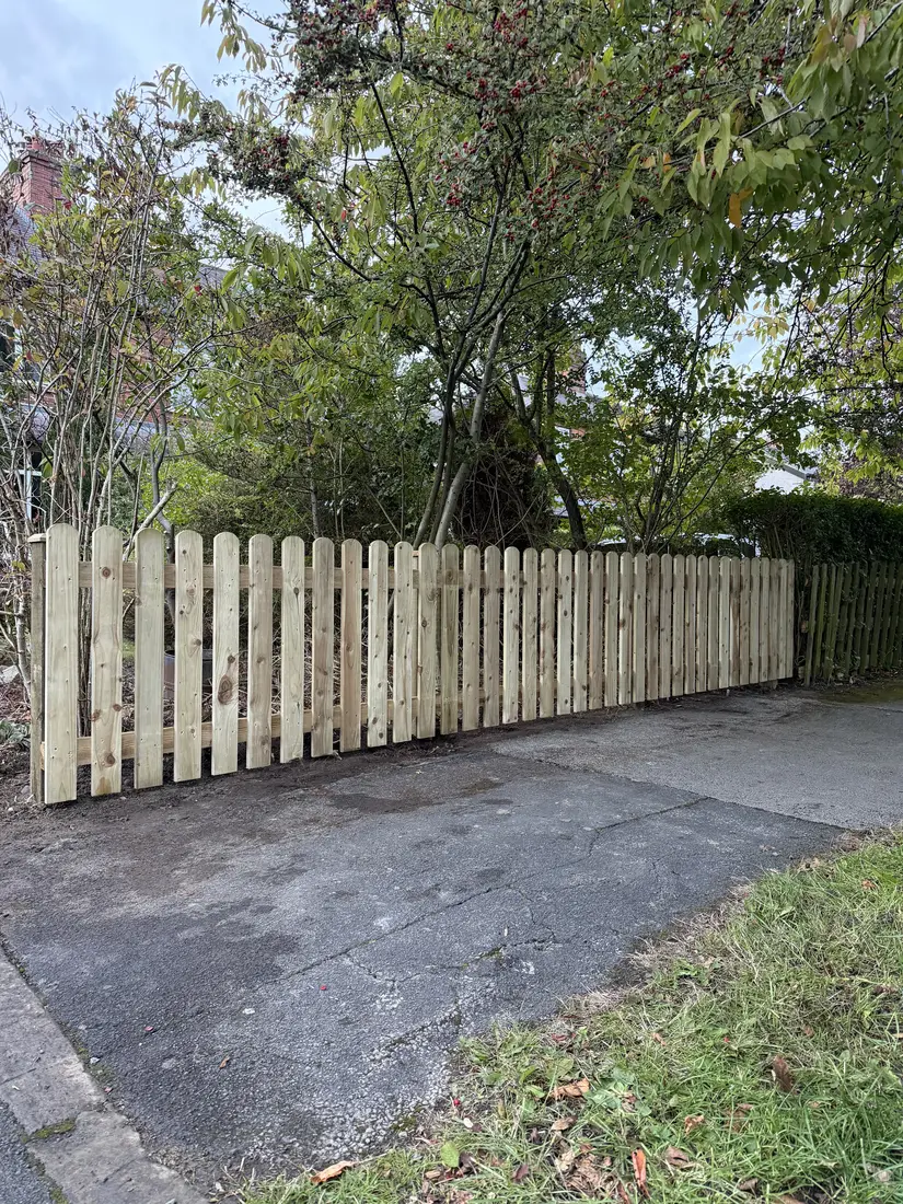 New timber picket fence installed alongside a residential driveway